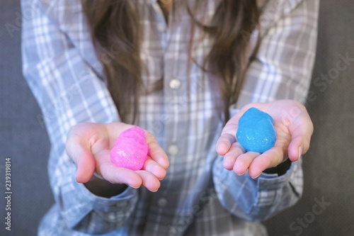 Two slimes pink and blue in woman's hands. Playing with slime.