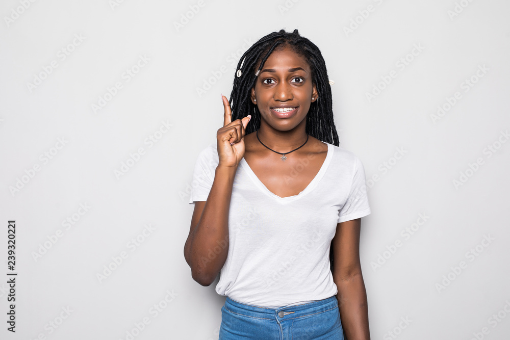 Φωτογραφία Waist up shot of joyful african girl wearing beige long sleeve t-shirt looking up, pointing finger at copy space above her head