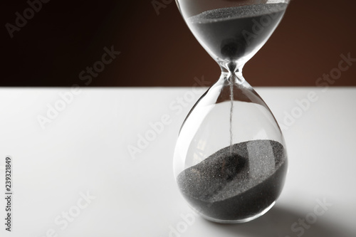 Crystal hourglass with falling sand on white table. Deadline concept