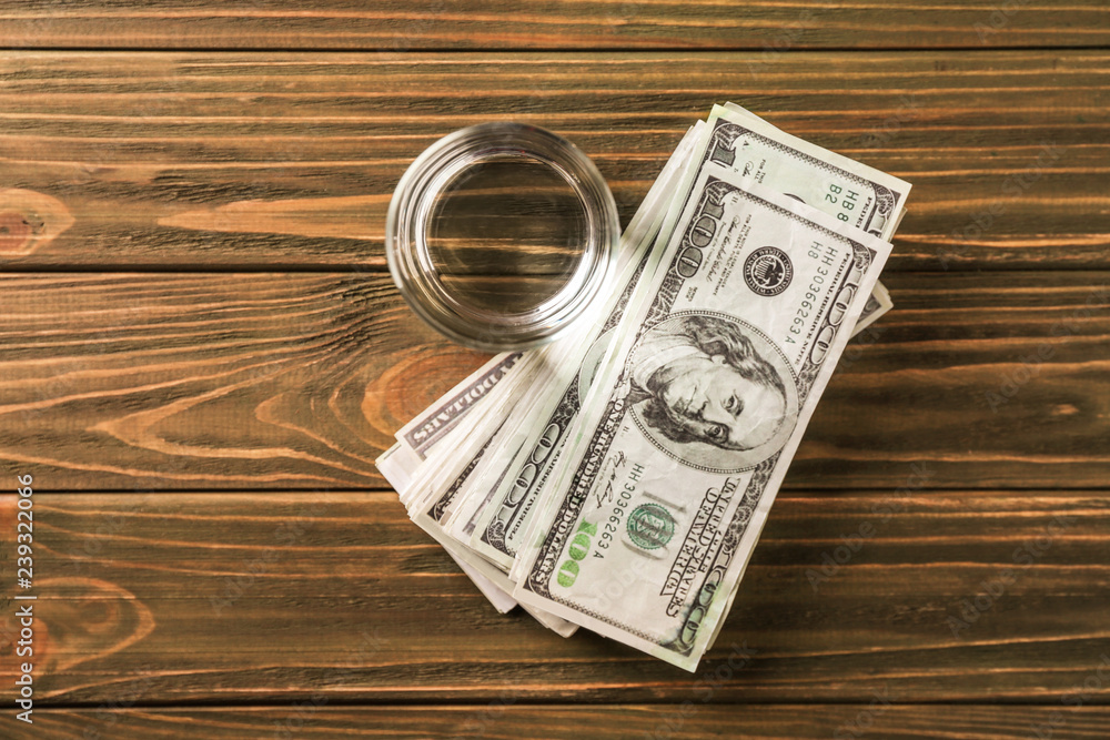 Glass of fresh water with dollar banknotes on wooden table Glass of fresh water with dollar banknotes on wooden table