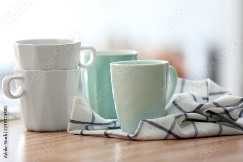 Clean kitchen towel with cups on wooden table