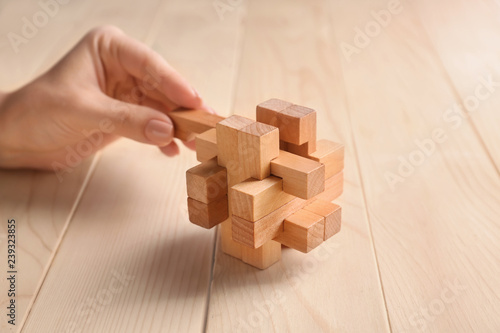 Female hand with brain teaser on wooden background