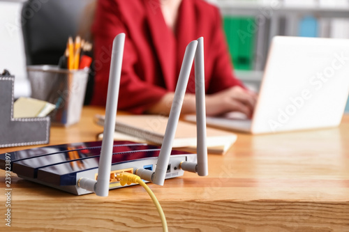 Modern wi-fi router on wooden table in office photo