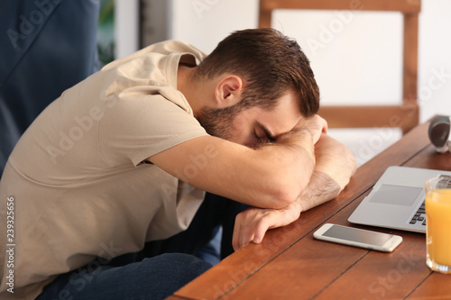 Tired young man sitting at table