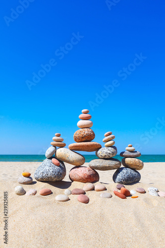 Canvas Print Rock zen pyramid of colorful pebbles on a sandy beach on the background of the sea