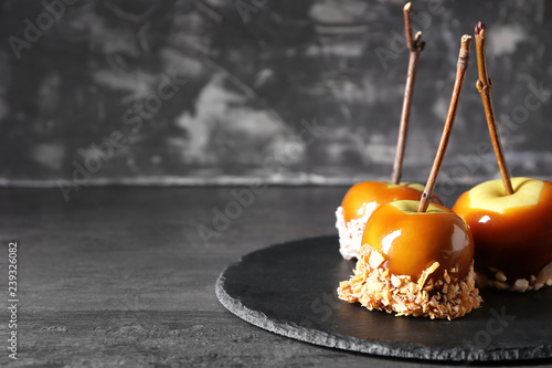 Delicious caramel apples with tree branches on slate plate photo