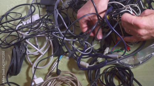 Man untangling tangled cables. Closeup.