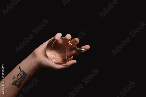 Woman holding bottle of perfume on dark background