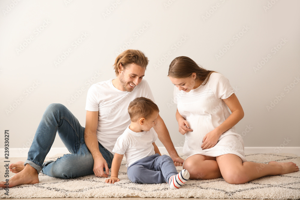 Portrait of happy family on carpet near white wall Portrait of happy family on carpet near white wall