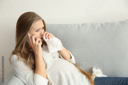 Young pregnant woman talking by phone and crying because of mood change