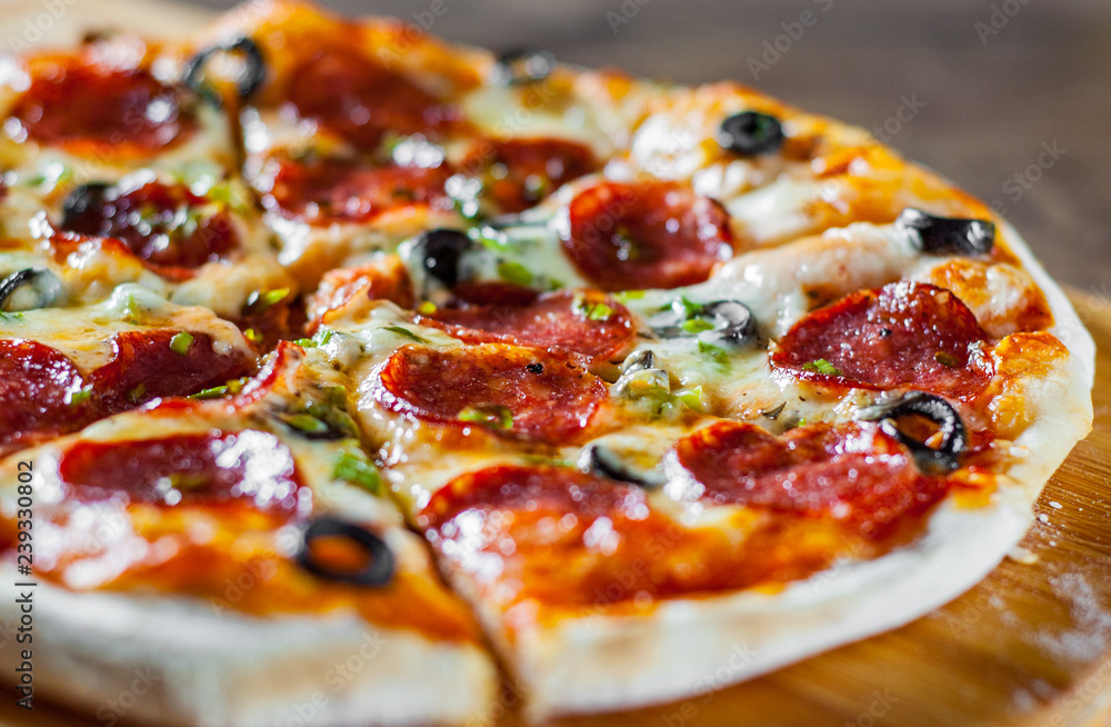 Pizza with Mozzarella cheese, pepperoni, tomato, pepper, olive, salami. Italian pizza on wooden table background