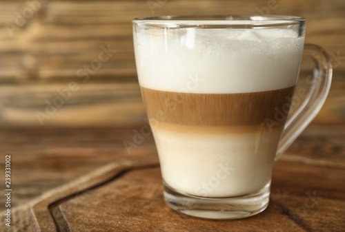 Glass cup of tasty aromatic latte on wooden board