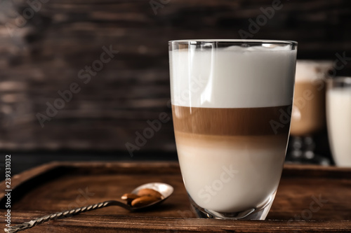 Glass of tasty aromatic latte on wooden board