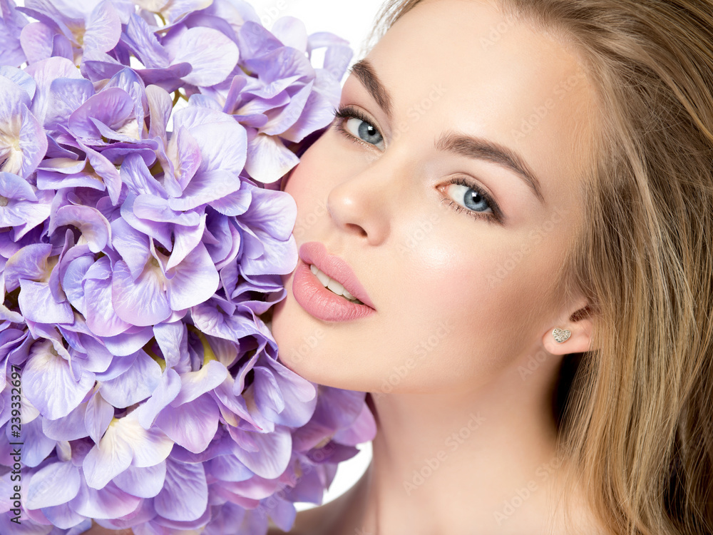 Beautiful young blonde woman with flowers near face Beautiful young blonde woman with flowers near face