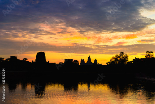 Angkor Wat dramatic sky at dawn main facade silhouette reflection on water pond. World famous temple in Cambodia.