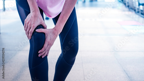 Woman runner having knee injured during exercise outside.