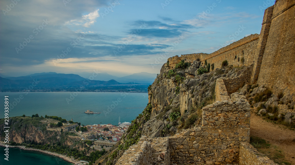 fortress ruin on top of rock above sea and medieval small city alone bay shoreline