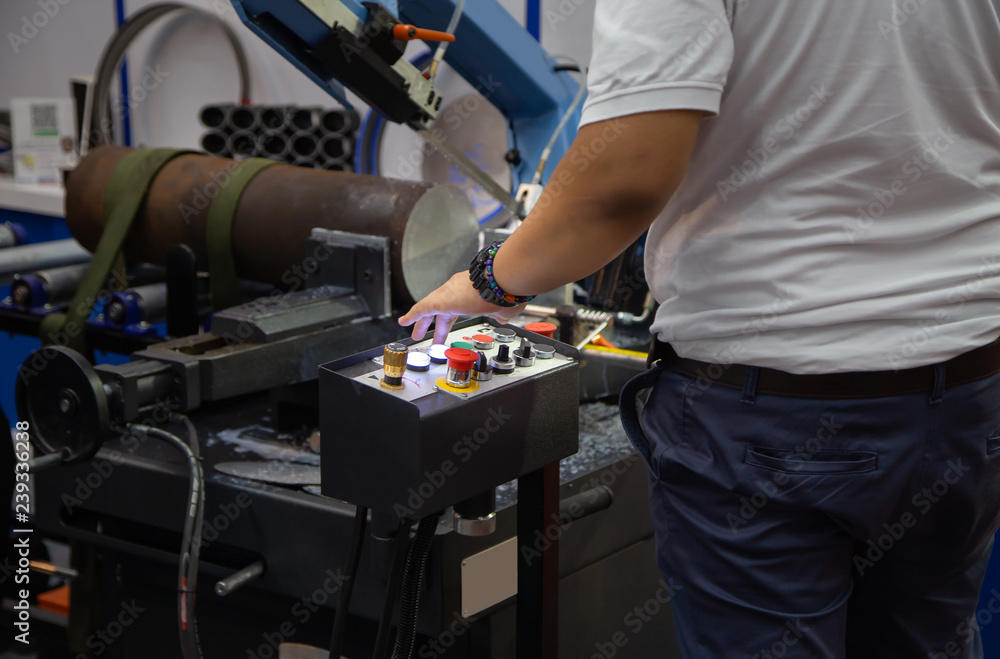 Industrial technician operate band saw machine cutting metal workpiece. Industrial metalworking machinery.