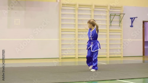 Young boy in traditional blue yifu clothes for tai chi training nanquan exercise in sport club. Boy teenager practising Chinese martial art Wushu while workout. Chinese martial art tai chi concept photo