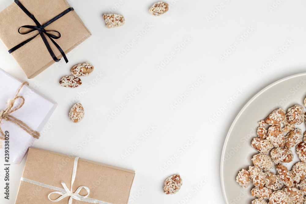 Frame from gifts in craft paper, sweet caramel nuts, plate on white background. Congratulation, Christmas, Birthday, recipe concept. Top view, flat lay, copy space, layout design Frame from gifts in craft paper, sweet caramel nuts, plate on white background. Congratulation, Christmas, Birthday, recipe concept. Top view, flat lay, copy space, layout design