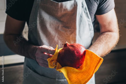 Ripe juicy large pomegranate in male hands - cooking in the kitchen according to the recipe