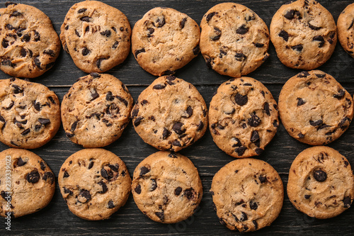 Tasty cookies with chocolate chips on dark wooden table