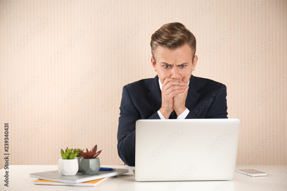Stressed young businessman at table on light background Stressed young businessman at table on light background