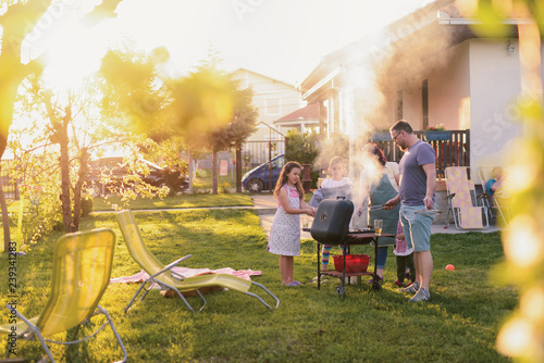 Picture of big happy family making barbeque in their backyard. Family time on sunny summer day.