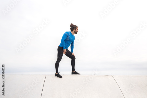 young man with long hair wearing sport cloth standing in front of the stairs