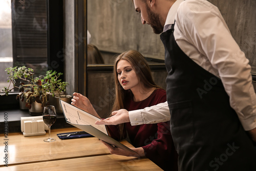 Young waiter showing woman ...