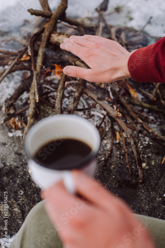 Man hands hold a cup of hot coffee on outdoor. Concept adventure active vacations outdoor. Winter camping