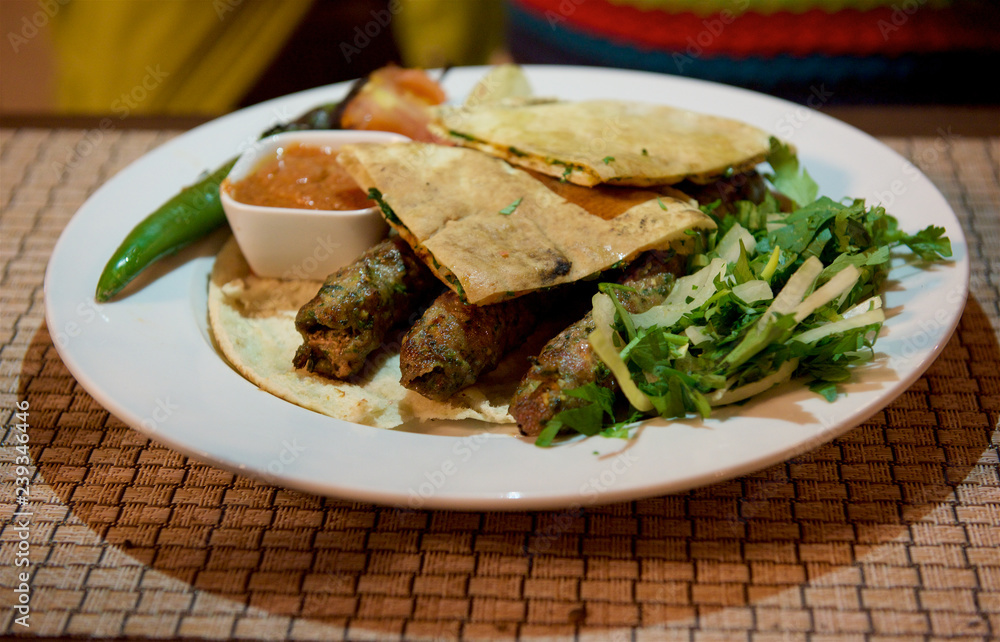 Kibbeh oriental restaurant beef, lamb, goat or camel meat served with fried green salad,pita, iolated.Travel to Middle East country Kingdom of Jordan - side view of plate with camel meat.Jordan food