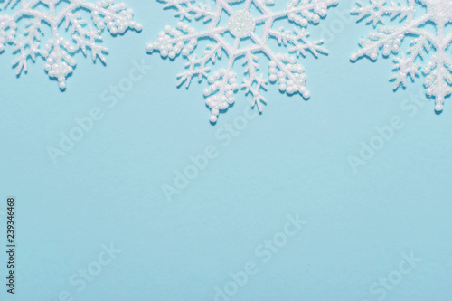 White glitter snowflake composition on a pastel blue background