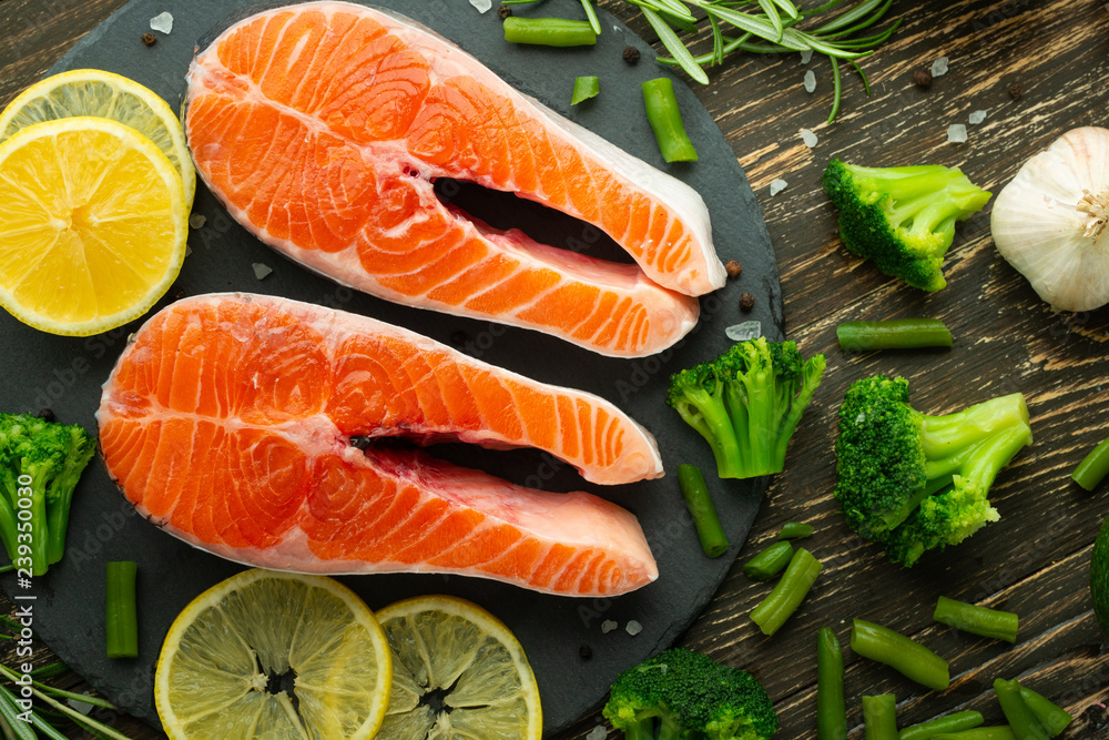 Raw salmon fillets and ingredients, vegetables for cooking on a dark background in a rustic style. Top view, flat-lay, healthy food and clean. Raw salmon fillets and ingredients, vegetables for cooking on a dark background in a rustic style. Top view, flat-lay, healthy food and clean.