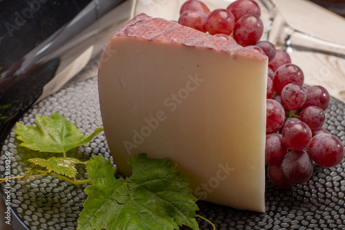 Traditional Spanish cheese, Murcian wine cheese from goat milk with rind washed in red wine, served with fresh ripe grapes photo