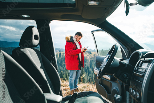 man standing near car with drone controller taking picture. view through car