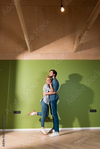loving family couple hugging by green wall in apartment © LIGHTFIELD STUDIOS