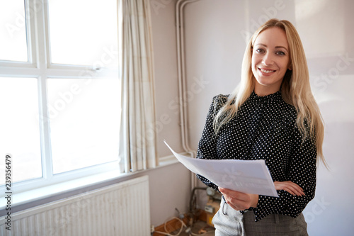 Portrait Of Female Realtor Looking At House Details In Property For Renovation photo