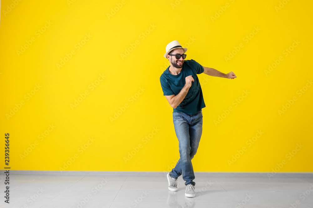 Handsome young man dancing near color wall - obrazy, fototapety, plakaty 
