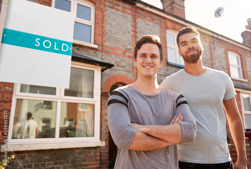 Portrait Of Two Men Standing Outside New Home With Sold Sign Stock
