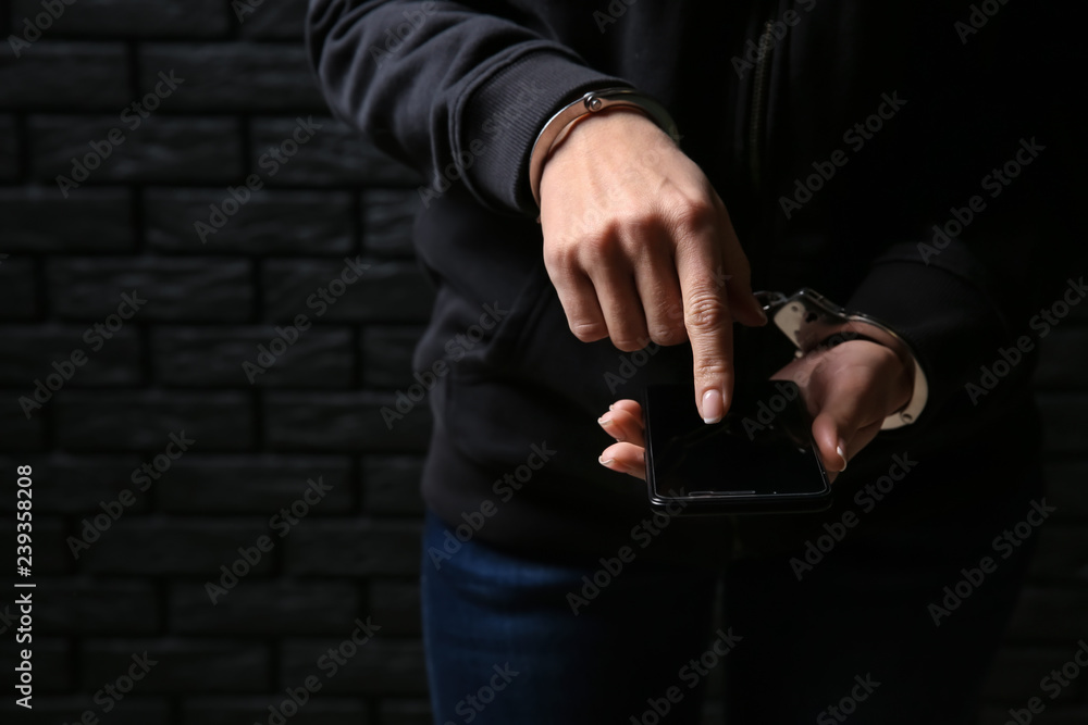Woman in handcuffs with mobile phone on dark background. Concept of addiction