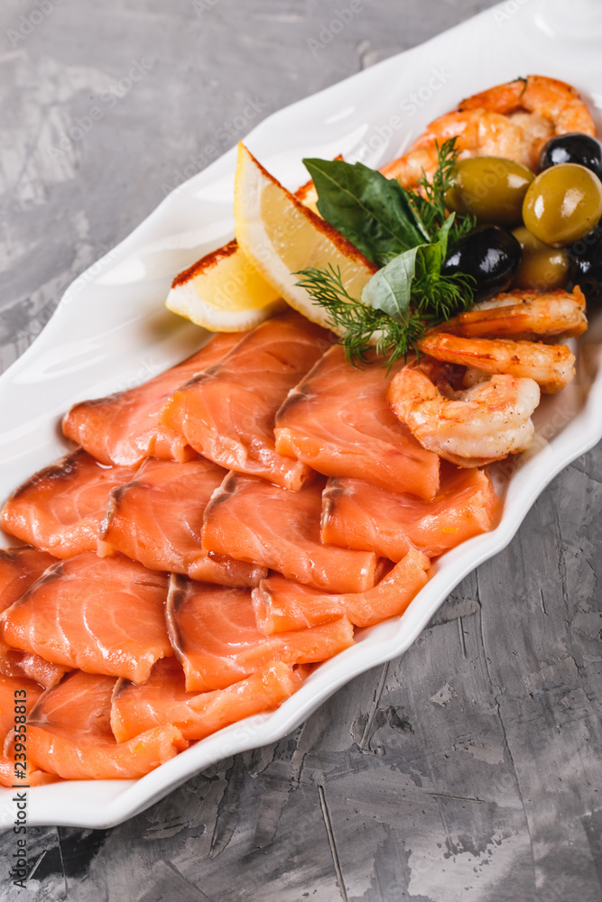 Seafood platter with salmon slice, shrimp, slices fish fillet, decorated with olives and lemon in plate over rustic background. Mediterranean appetizers Seafood platter with salmon slice, shrimp, slices fish fillet, decorated with olives and lemon in plate over rustic background. Mediterranean appetizers