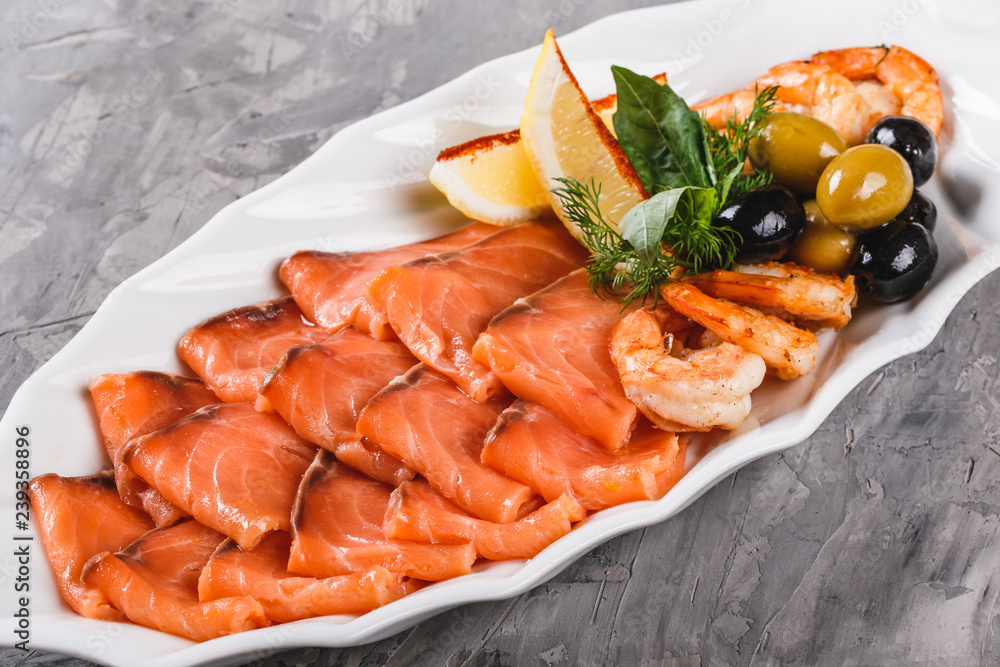Seafood platter with salmon slice, shrimp, slices fish fillet, decorated with olives and lemon in plate over rustic background. Mediterranean appetizers Seafood platter with salmon slice, shrimp, slices fish fillet, decorated with olives and lemon in plate over rustic background. Mediterranean appetizers