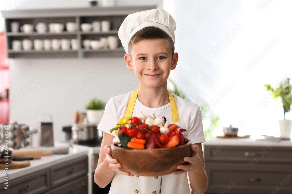 Cute little chef with vegetables in kitchen Cute little chef with vegetables in kitchen