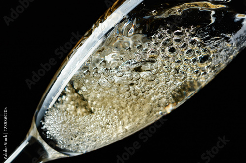 Glass of splashing champagne isolated on black. © Igor Normann