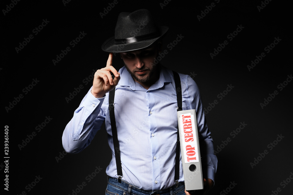 Detective holding folder with text TOP SECRET on dark background Detective holding folder with text TOP SECRET on dark background