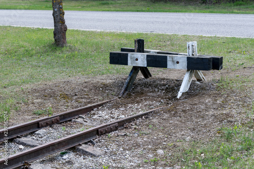 Railroad tracks stretches and green grass and trees. Railway road environment background..End of the rail.