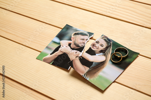 Torn photo of happy couple on wooden background. Concept of divorce photo