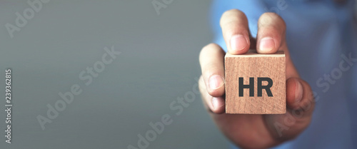 Man holding HR word on wooden cube.