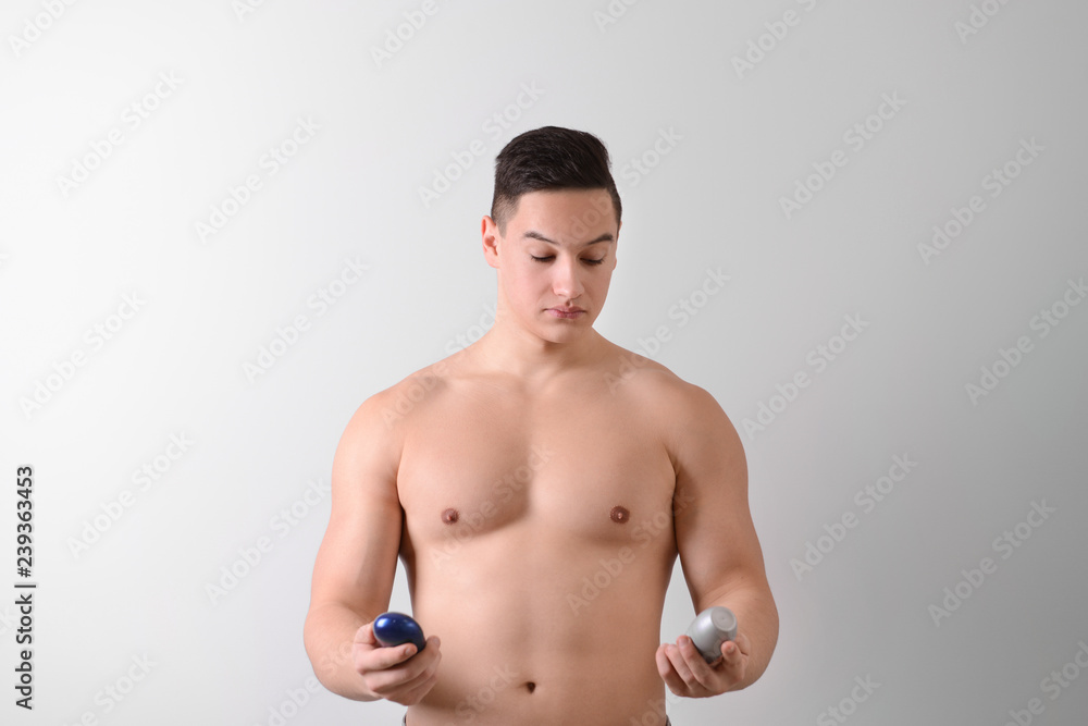 Fototapeta premium Young man with different types of deodorant on light background